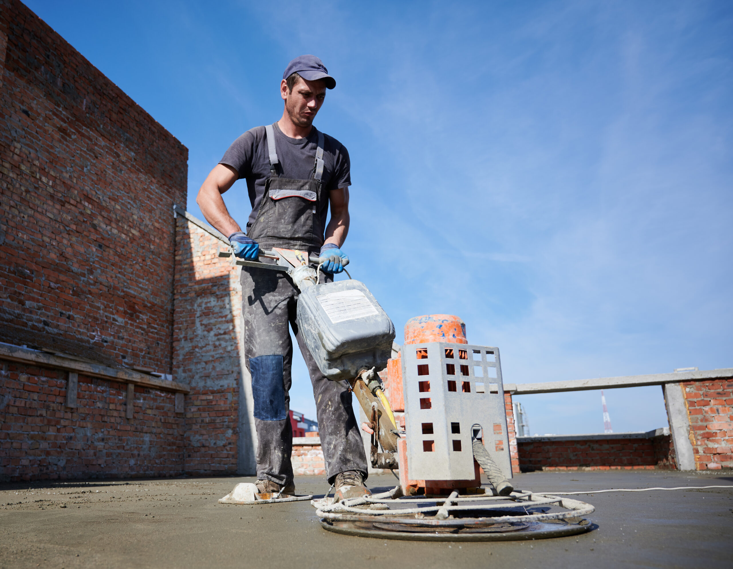 Worker using power trowel machine at construction site